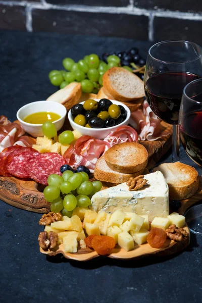 Bandeja de queso, pan, frutas y embutidos al vino en backg oscuro — Foto de Stock