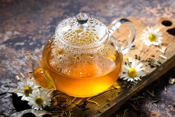 Стеклянный чайник ароматного ромашкового чая на темном фоне, закрыть — стоковое фото