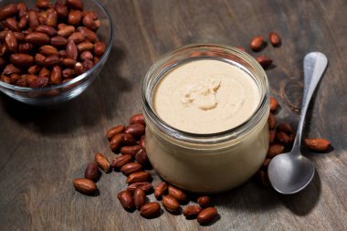 ahşap bir arka plan üzerinde cam bir kavanozda fıstık ezmesi, üst görünümü