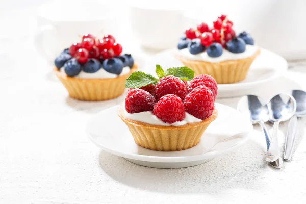 Mini tortas com creme e bagas na mesa branca — Fotografia de Stock