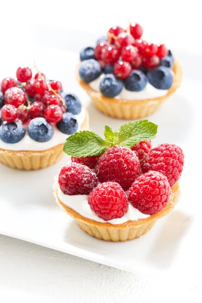 Mini sütemények tejszín és bogyós gyümölcsök, felülnézet függőleges — Stock Fotó