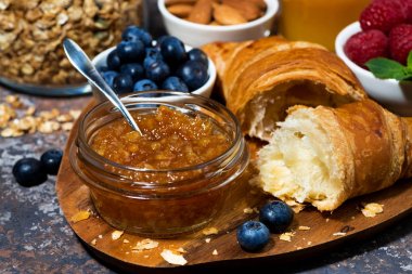 kruvasan, portakal reçeli ve çilek ahşap bir tahta üzerinde