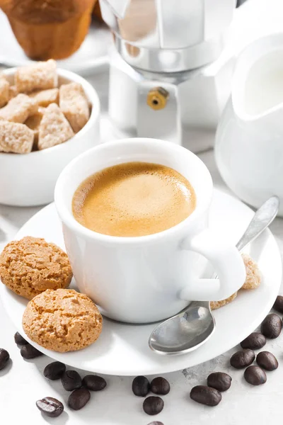 cup of espresso and cookies on a white table, vertical