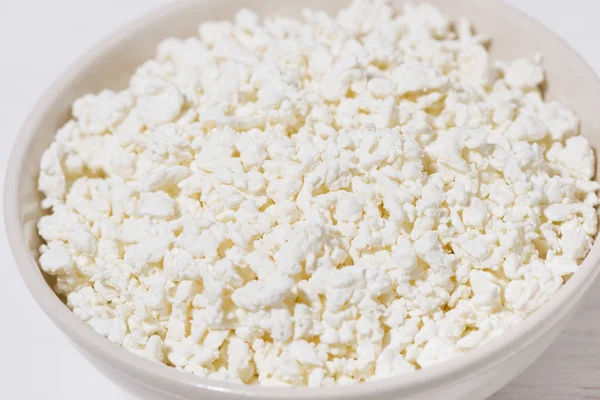 Bowl of fresh farm cottage cheese on a white wooden background — Stock Photo, Image