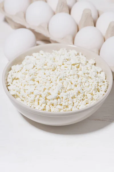 Bowl of fresh farm cottage cheese and eggs on a white background — Stock Photo, Image