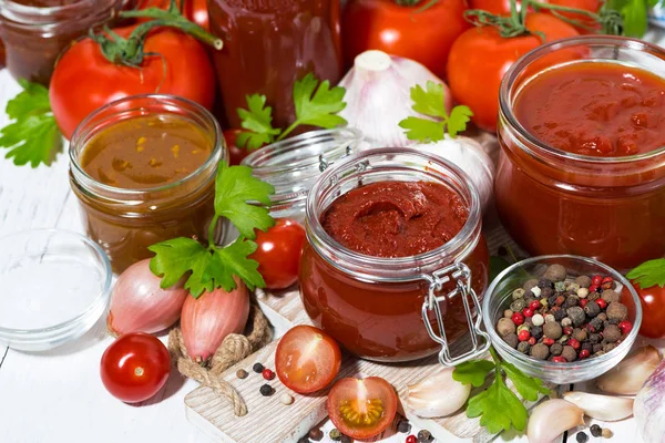 Sughi di pomodoro, pasta e ingredienti freschi sul tavolo di legno bianco — Foto Stock