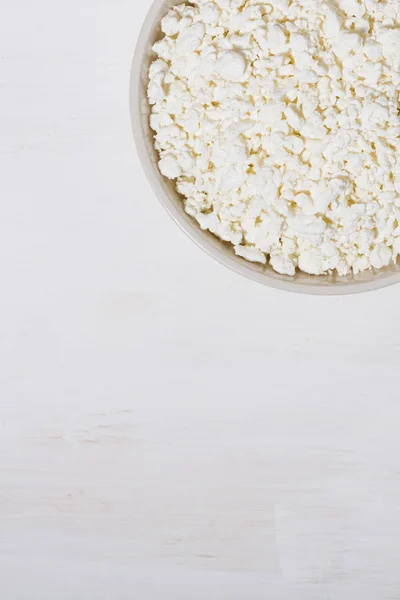Tazón de queso cottage granja fresca sobre un fondo de madera blanca — Foto de Stock