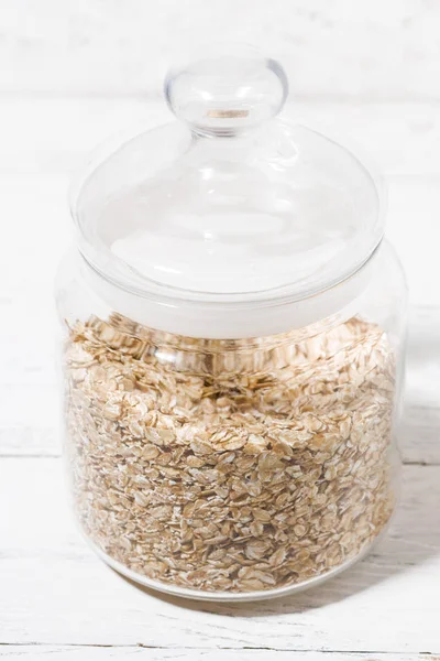 Glass jar with oat flakes, closeup vertical — Stock Photo, Image