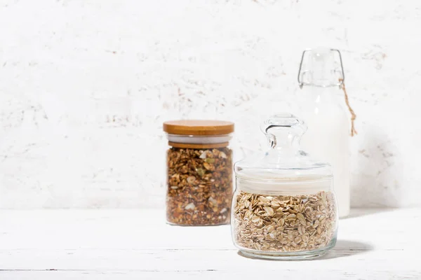 Jarra de vidro com flocos de aveia, granola e garrafa de leite — Fotografia de Stock