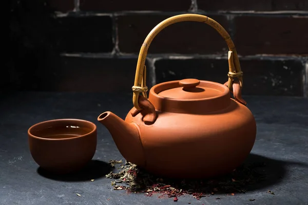 Brown ceramic teapot and cup of tea on a dark background — Stock Photo, Image