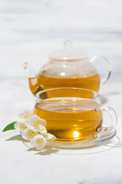 Чашка стекла и чайник с жасминовый зеленый чай на белом фоне — стоковое фото