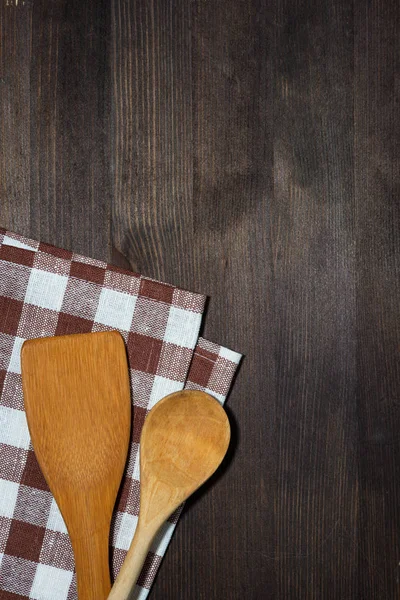 Paño de cocina, cucharas de madera, fondo de madera, vista superior vertical — Foto de Stock