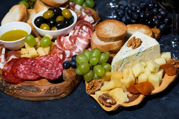Bandeja de queso en una tabla de madera, pan, frutas y embutidos — Foto de Stock