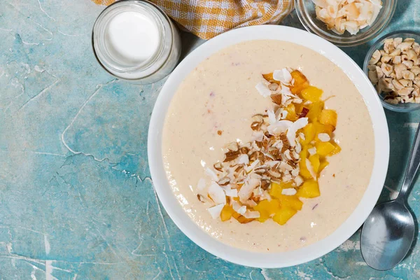 Semangkuk smoothie sehat dengan mangga, kelapa dan kacang untuk sarapan — Stok Foto