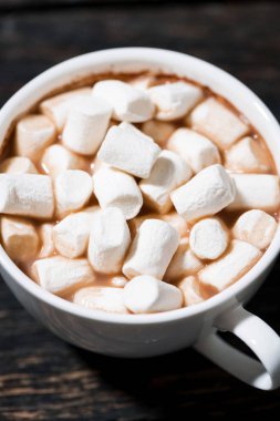 Bir fincan kakao, üzerinde marşmelov olan tahta bir masa, dikey.