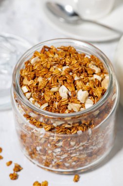Hindistan cevizi ve fındıklı tatlı granola kavanozu beyaz arka plan, dikey üst görünüm