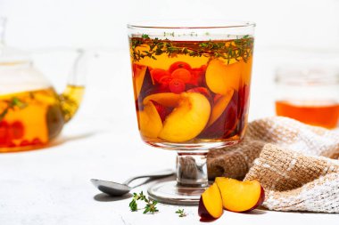 Beyaz arka planda taze erik, böğürtlen ve kekik aromalı siyah çay, yakın yatay