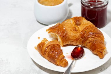 Taze kruvasan, kahve ve çilek reçeli, beyaz arka plan, yakın plan.