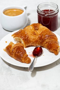 Taze kruvasan, kahve ve çilek reçeli, beyaz arka plan, dikey yakın plan