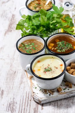 Ahşap arka planda bardaklarda sıcak çorba çeşitleri, dikey üst görünüm