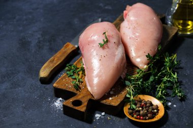 Kesme tahtasında çiğ tavuk göğsü ve taze kekik, üst manzara.