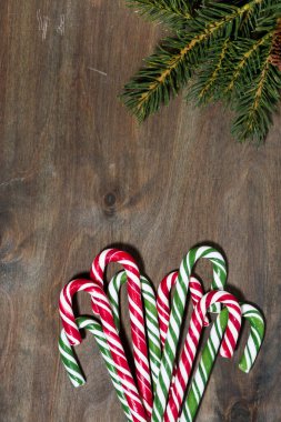 Yılbaşı şekeri çeşitleri ve gri arka planda köknar dalları, dikey üst görünüm