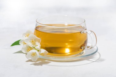 Beyaz arka planda yeşil çay bardağı ve yasemin, yakın yatay.