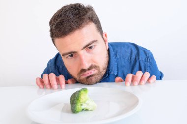 Man on diet feeling hungry and bored by vegetable meal clipart