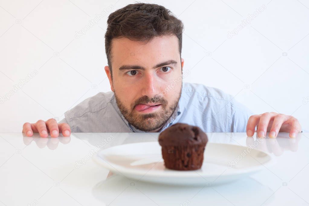 Sweet tooth man on diet tempted by chocolate muffin