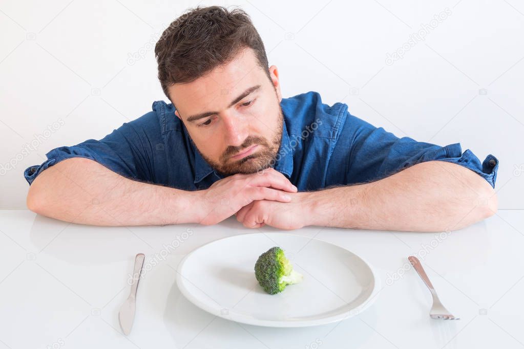 Bored man eating only low calorie lunch for diet