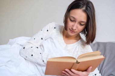 Yatakta kitap okuma ve rahatlatıcı sabah kadın