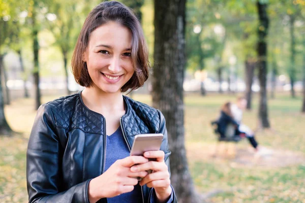 Joven Mujer Sonriente Sosteniendo Teléfono Móvil Parque Ciudad — Foto de Stock