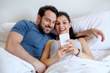 Çift yatakta smartphone tutarak aşık