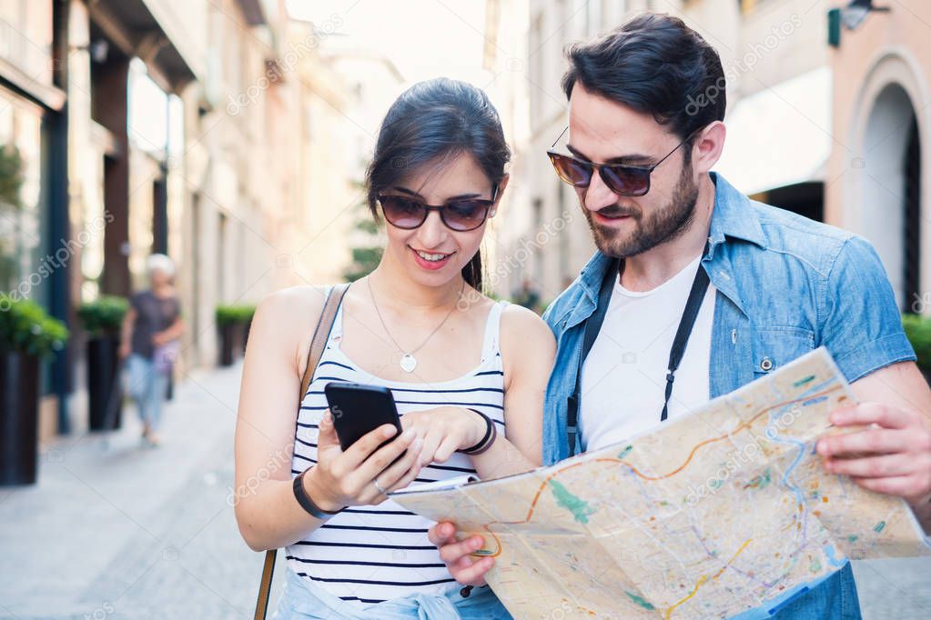 Happy tourists couple with mobile phone and map