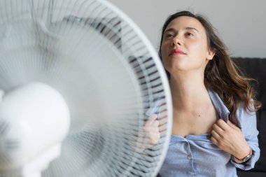 Young woman refreshing in front of a cooling fan clipart