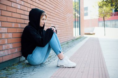 Yalnız kız portre kapüşonlu sweatshirt sonraki kentsel sokak duvar ile