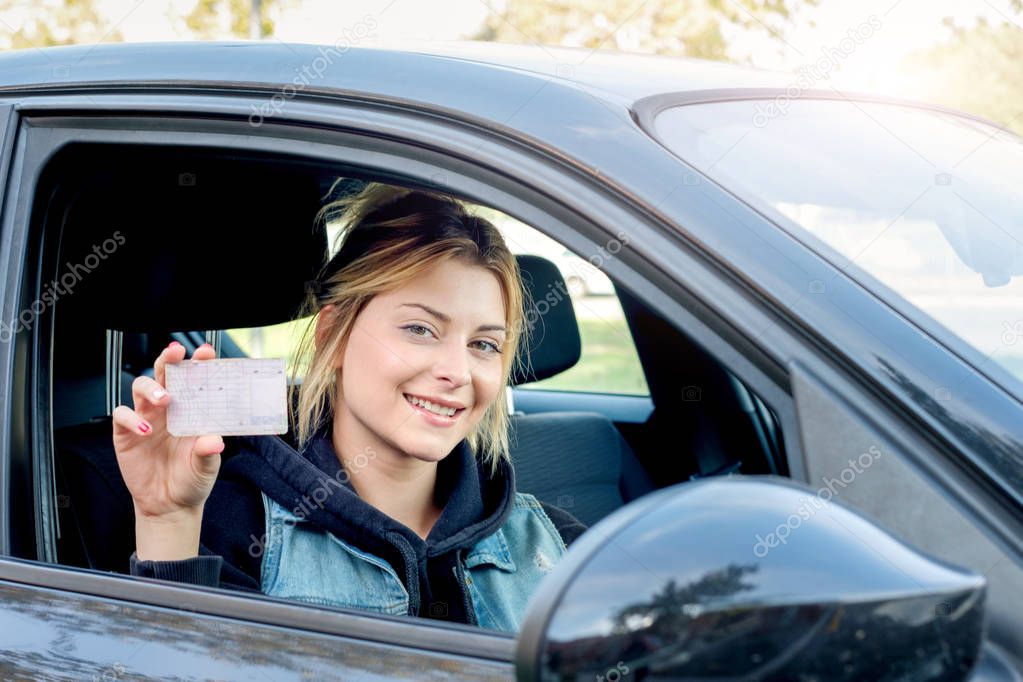 Young woman portrait sitting in her car and driving license