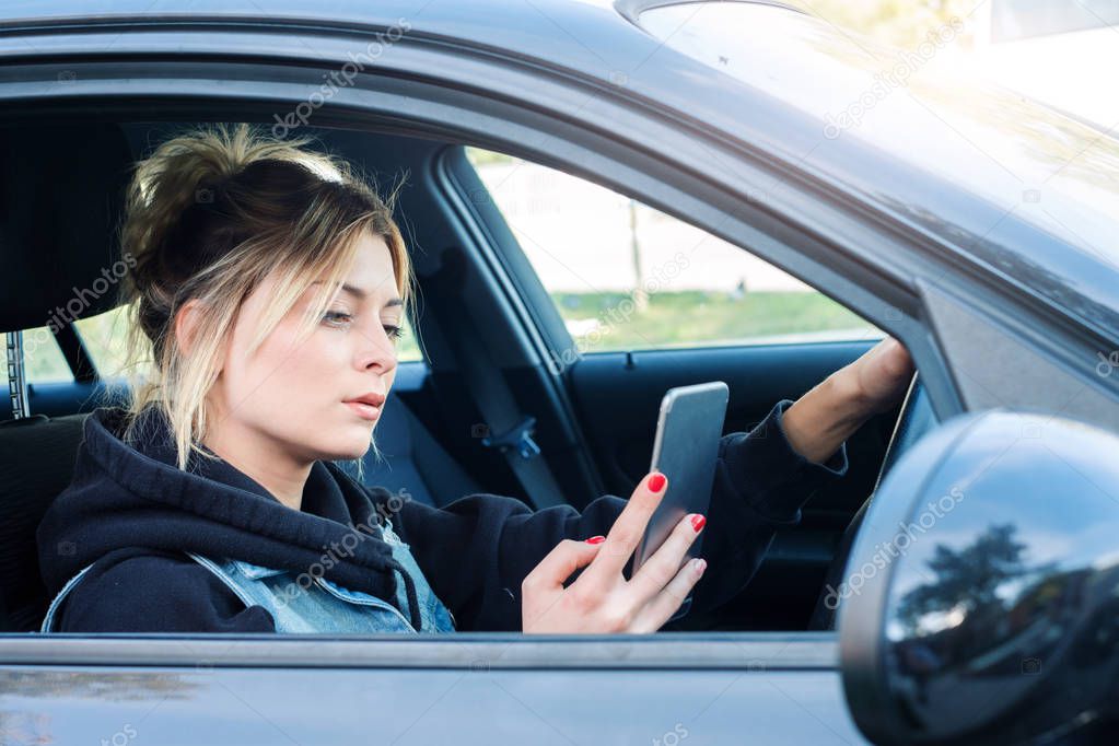 Woman driving car distracted by her mobile phone