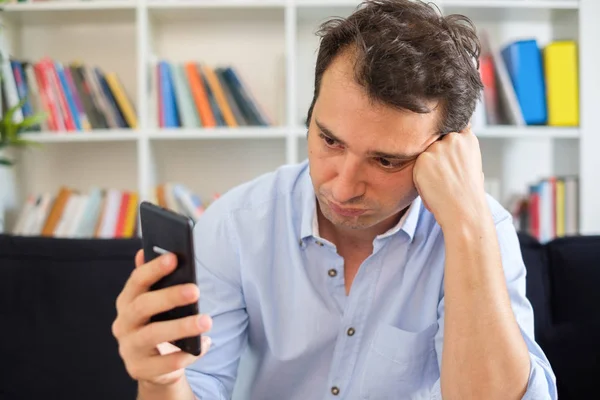 Sad man waiting for a message and watching mobile phone display