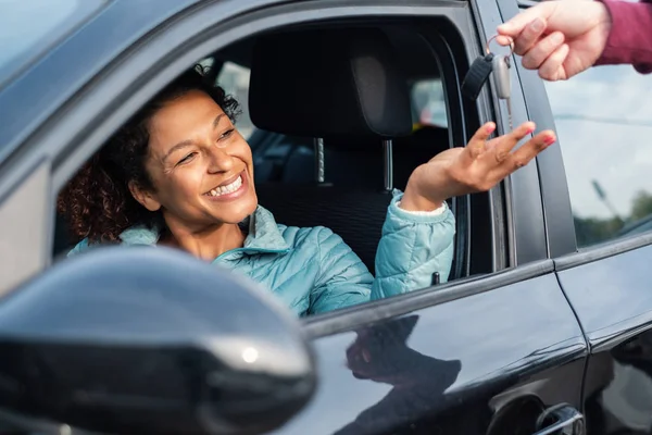 Black car driver woman smiling receiving new car keys and car