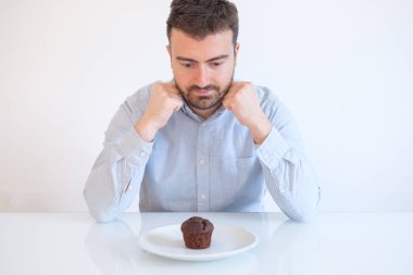 Adam tatlı tatlı çikolata kek kek için direnmeye çalışan diş ile