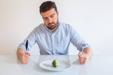 Fakir diyet yemek izleyen üzgün ve aç adamım