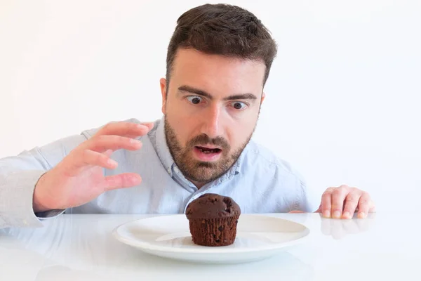 Man with sweet tooth trying to resist to sweet chocolate muffin cake