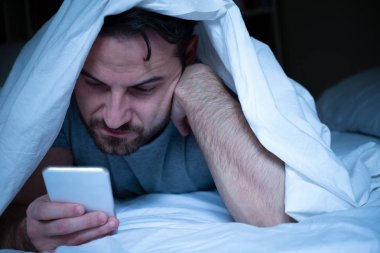 Cep telefonundan bir ileti için bekleyen endişeli adam