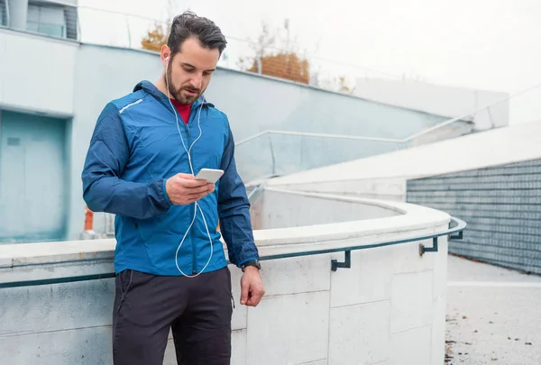 Runner sportsman holding mobile phone during workout