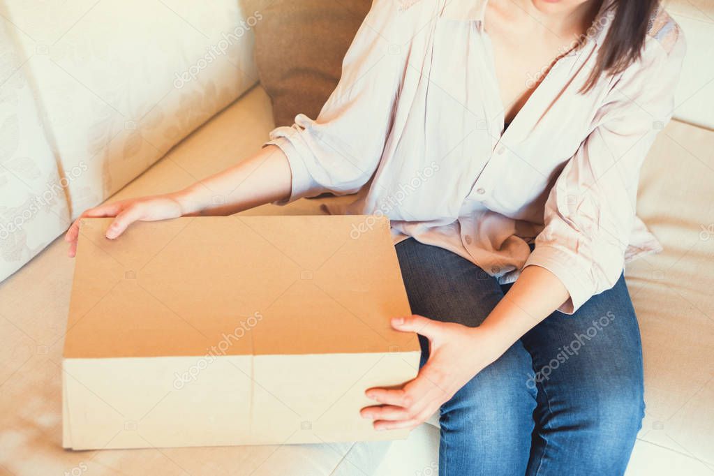 Young woman opening packet at home after home delivery