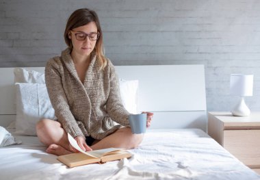 Evde yatakta kitap ile rahatlatıcı kadın