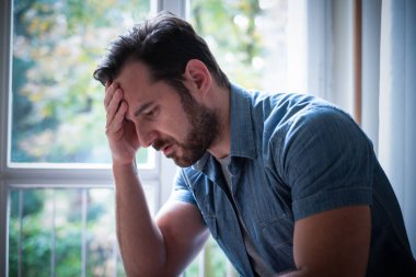 Endişeli adam pencereden dışarı düşünceli bakan