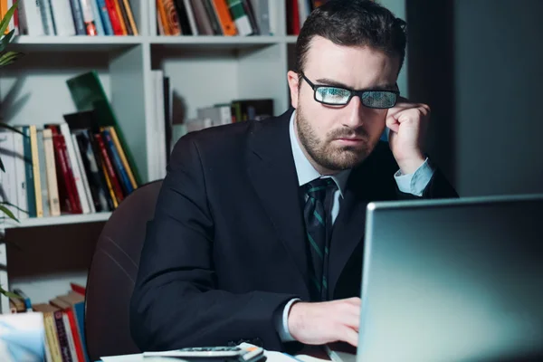 Sad and thoughtful businessman watching laptop display at night