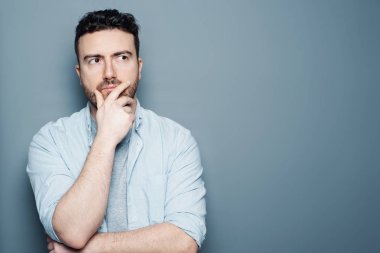 Gri bir arka plan karşı düşünceli bir adam portresi